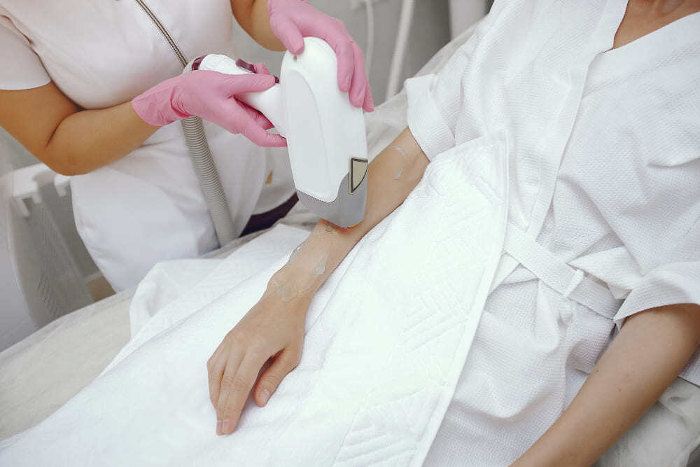 Femme se faisant épiler le bras par un médecin.