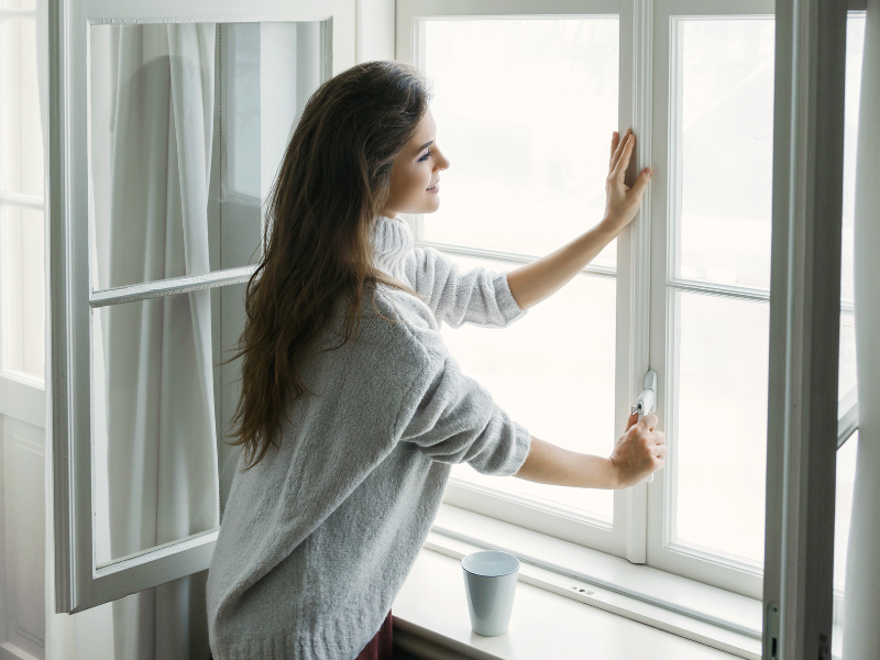 Femme qui aère sa maison pour prévenir les maladies hivernales