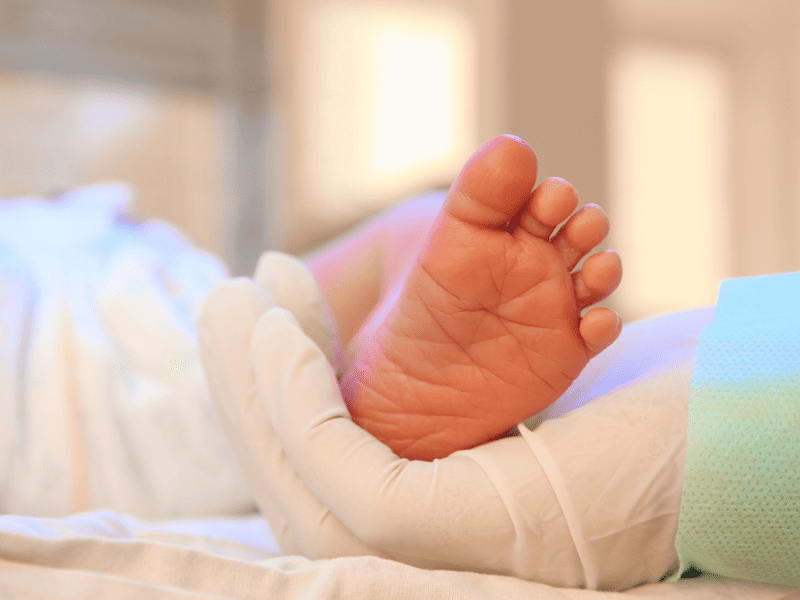 Main qui tient le pied d'un nourrisson dans le cadre d'un dépistage néonatal