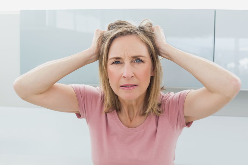 Femme en période de ménopause se tenant la tête car elle n'est pas bien.