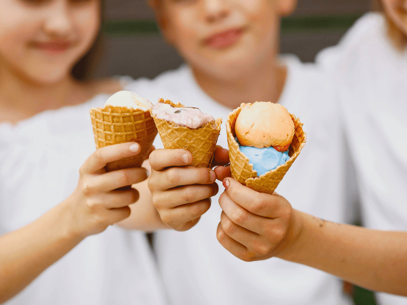 Enfants qui mangent des glaces et font des excès alimentaires pendant les vacances.