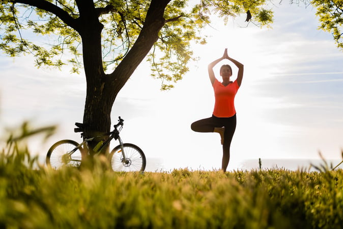 Femme arrêtée dans un parc, faisant du yoga et pratiquant de bonnes habitudes de vie.