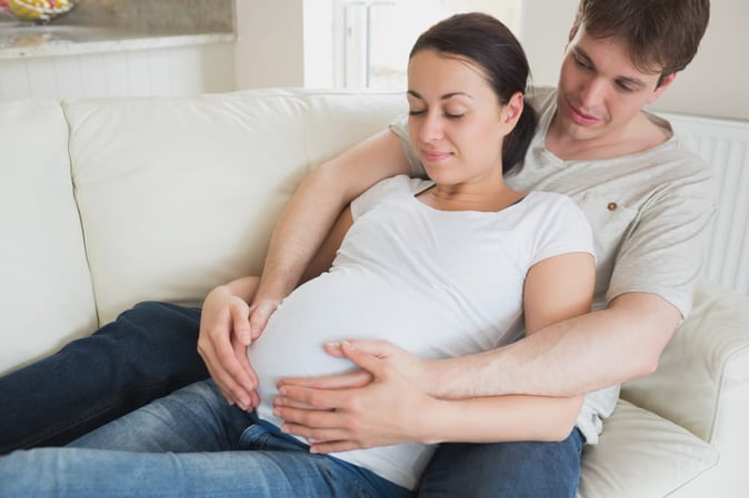 Femme enceinte et son mari en train de faire de l'haptonomie ensemble sur le ventre de la mère.