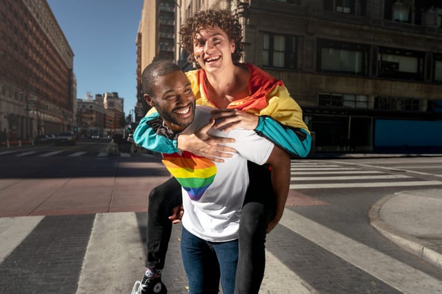Couple d'hommes homosexuels souriant dans la rue.