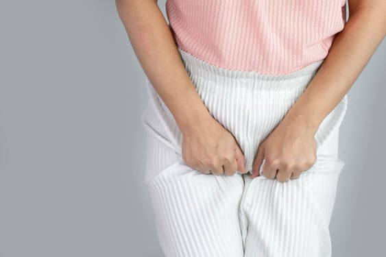Femme ayant une infection urinaire, se tenant le pantalon car elle a mal à la vessie.