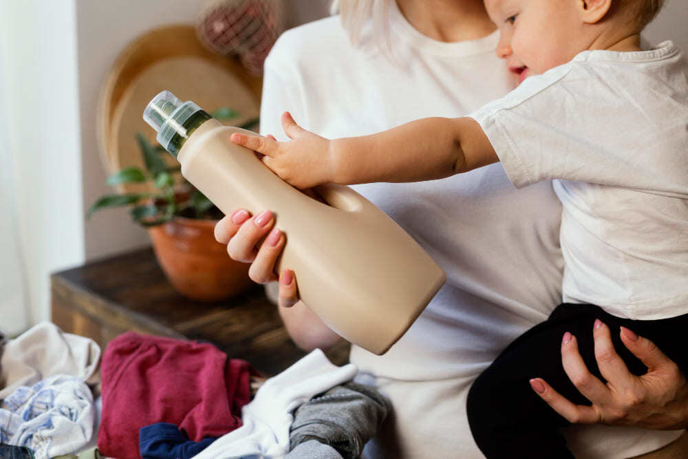 Enfant tenant un bidon de lessive dans les mains.