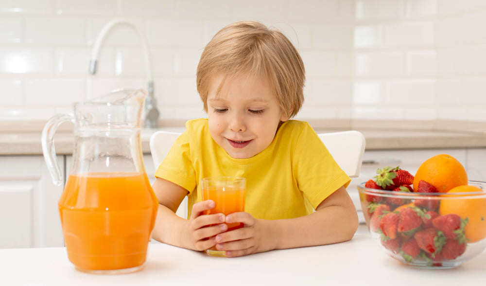 Enfant buvant du jus d'orange le matin avant d'aller à l'école.