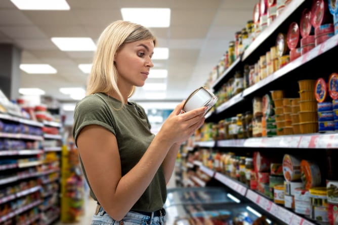 Femme regardant l'étiquetage d'un produit alimentaire.