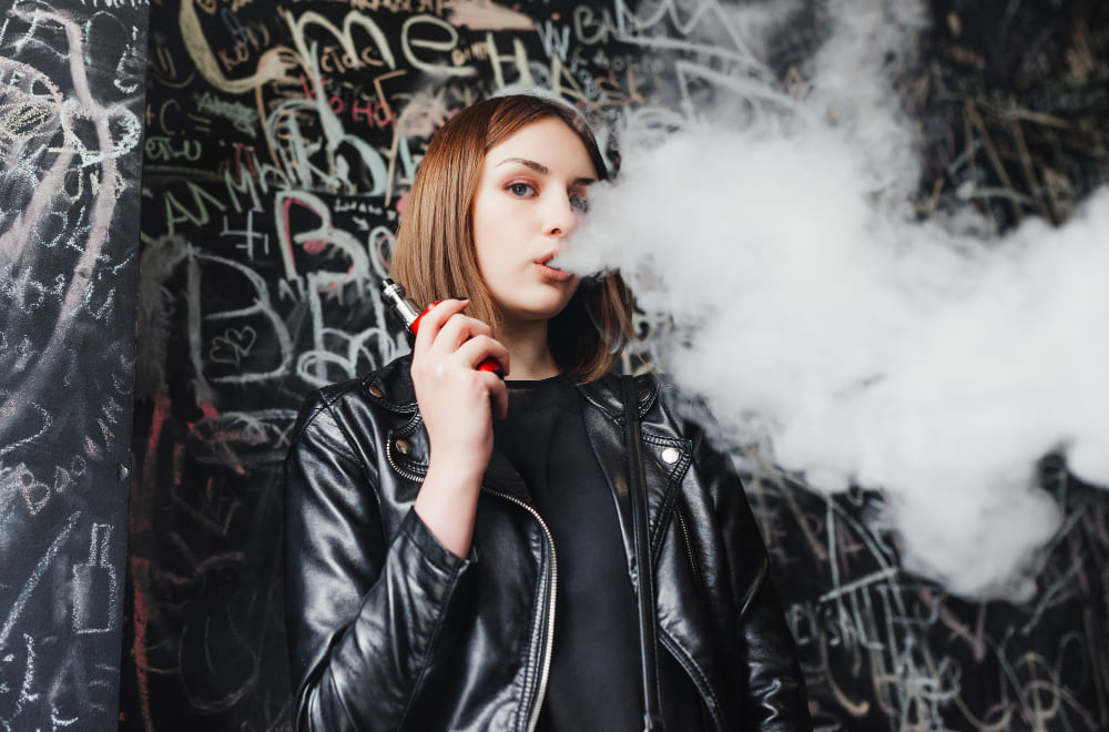 Adolescente qui vapote une cigarette électronique.
