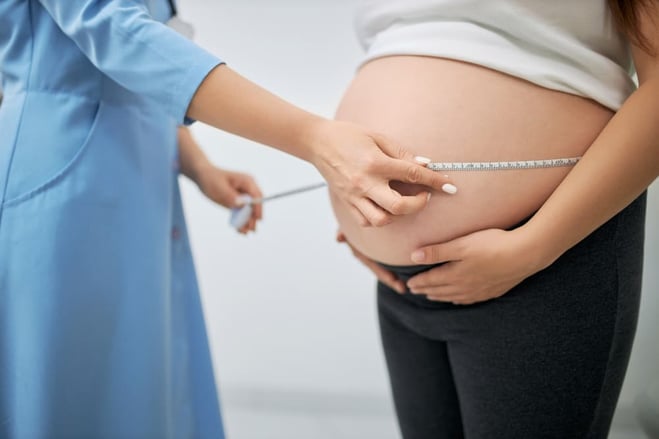 Médecin prenant les mesures du ventre de la femme enceinte, vérification du poids.