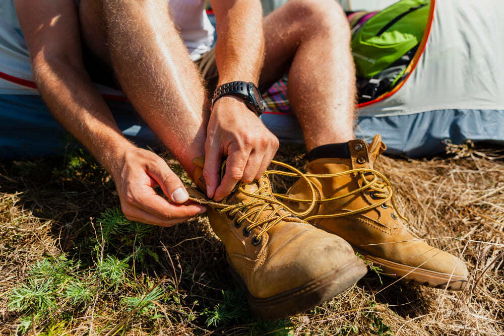 Homme qui lace ses chaussures de randonnée prévues pour la marche.