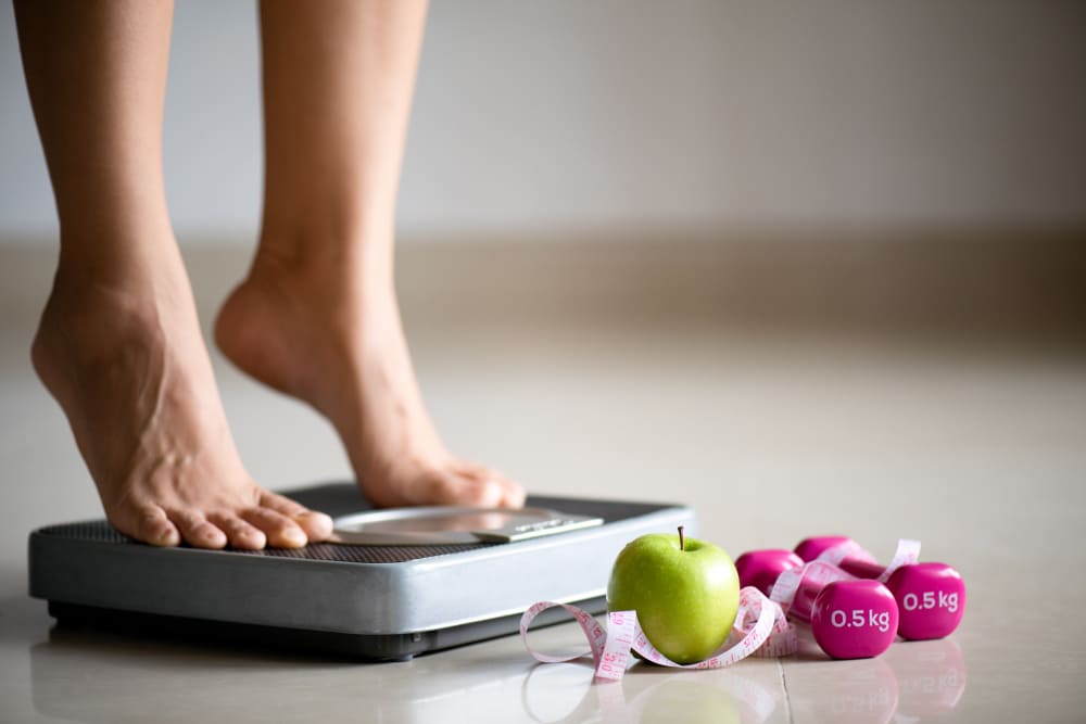 Femme qui se pèse après son sport pour préparer les beaux jours.