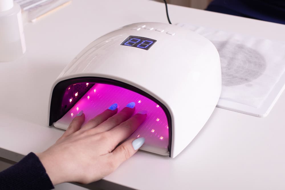 Femme utilisant une lampe UV pour ses ongles : préparer les beaux jours.