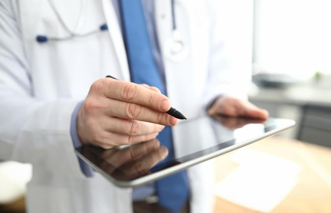 Médecin tenant une tablette numérique faisant une prescription électronique.