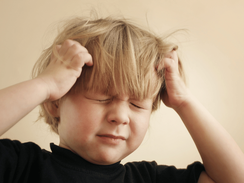 Enfant qui se gratte la tête parce qu'il a des poux.