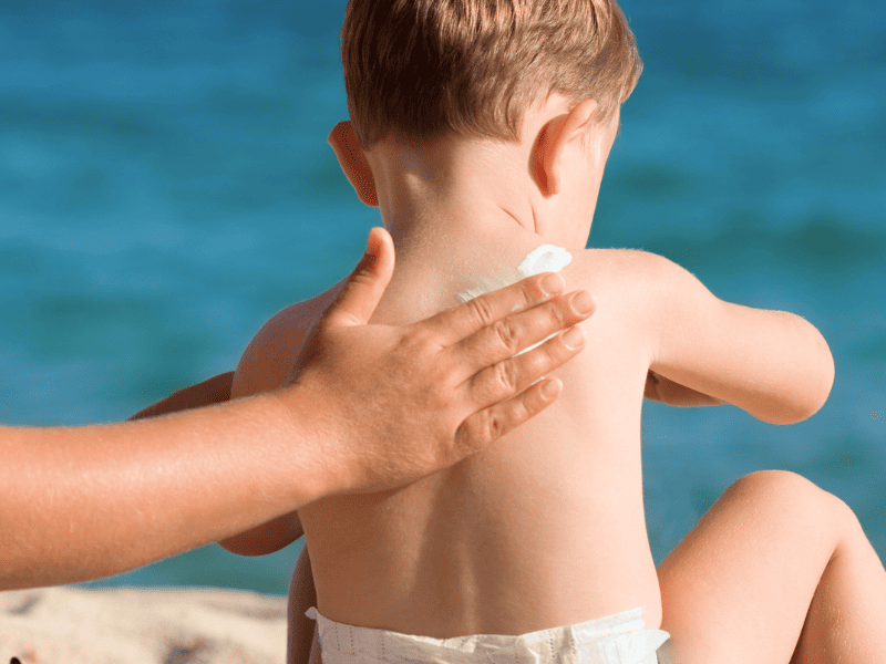 Application de la crème solaire sur un enfant pour le protéger des dangers du soleil.