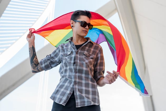 Homme transgenre tenant le drapeau LGBT+.