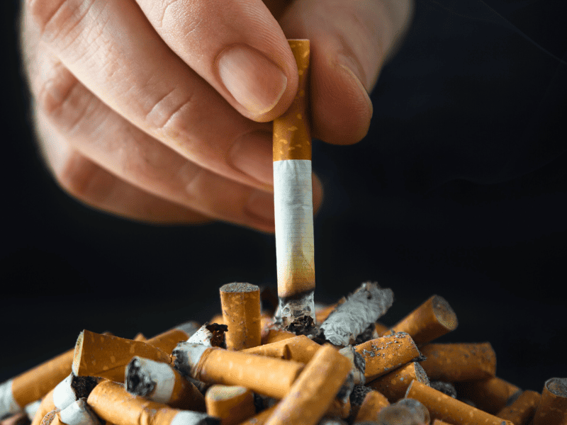 Homme qui écrase une cigarette sur un tas de cigarettes