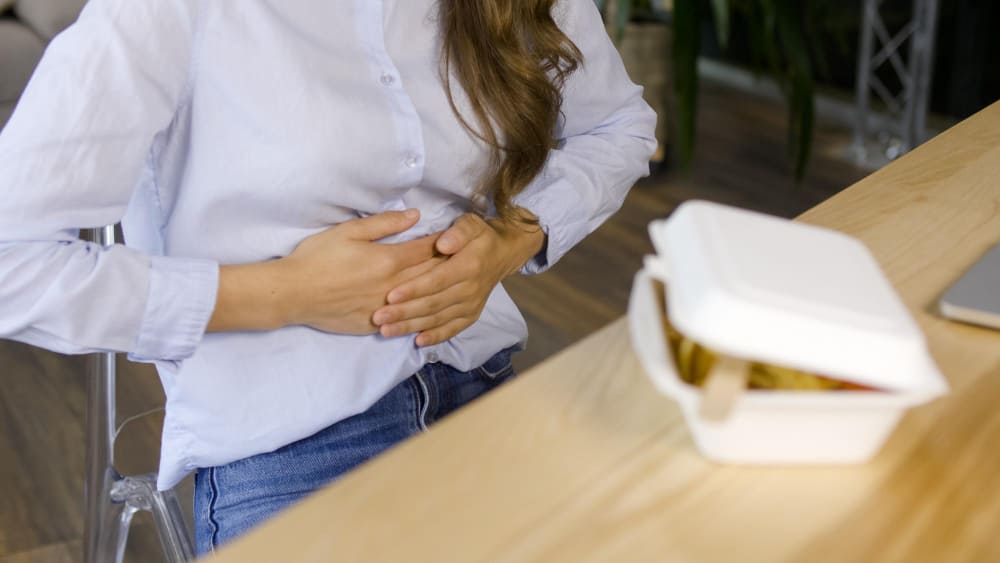 Femme ayant des douleurs abdominales après avoir mangé dans un restaurant rapide.