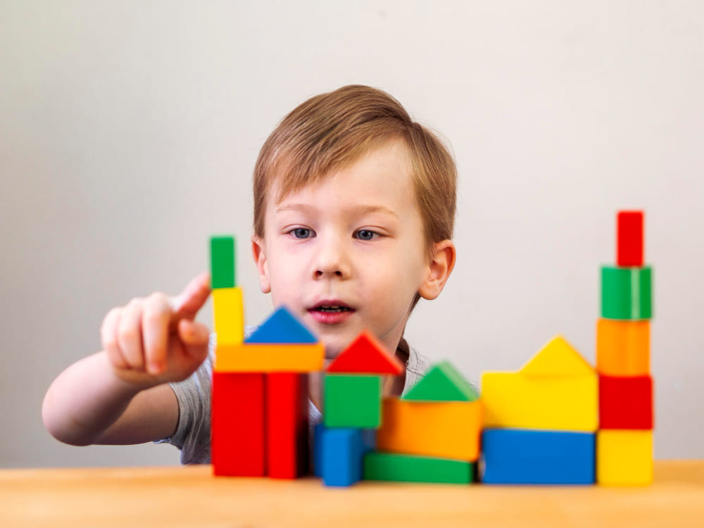 Enfant potentiellement autiste qui fixe des cubes de couleurs.