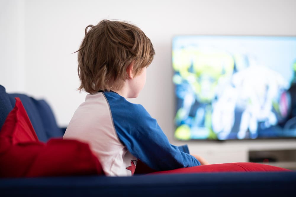 Enfant qui fait un test oculaire pour un trouble autistique en regardant la télé.