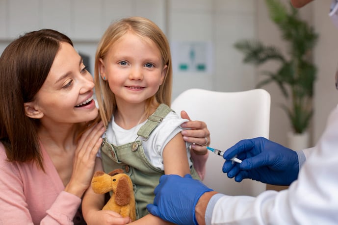 Une enfant se fait vacciner par un professionnel de la santé contre la grippe accompagné de sa mère.