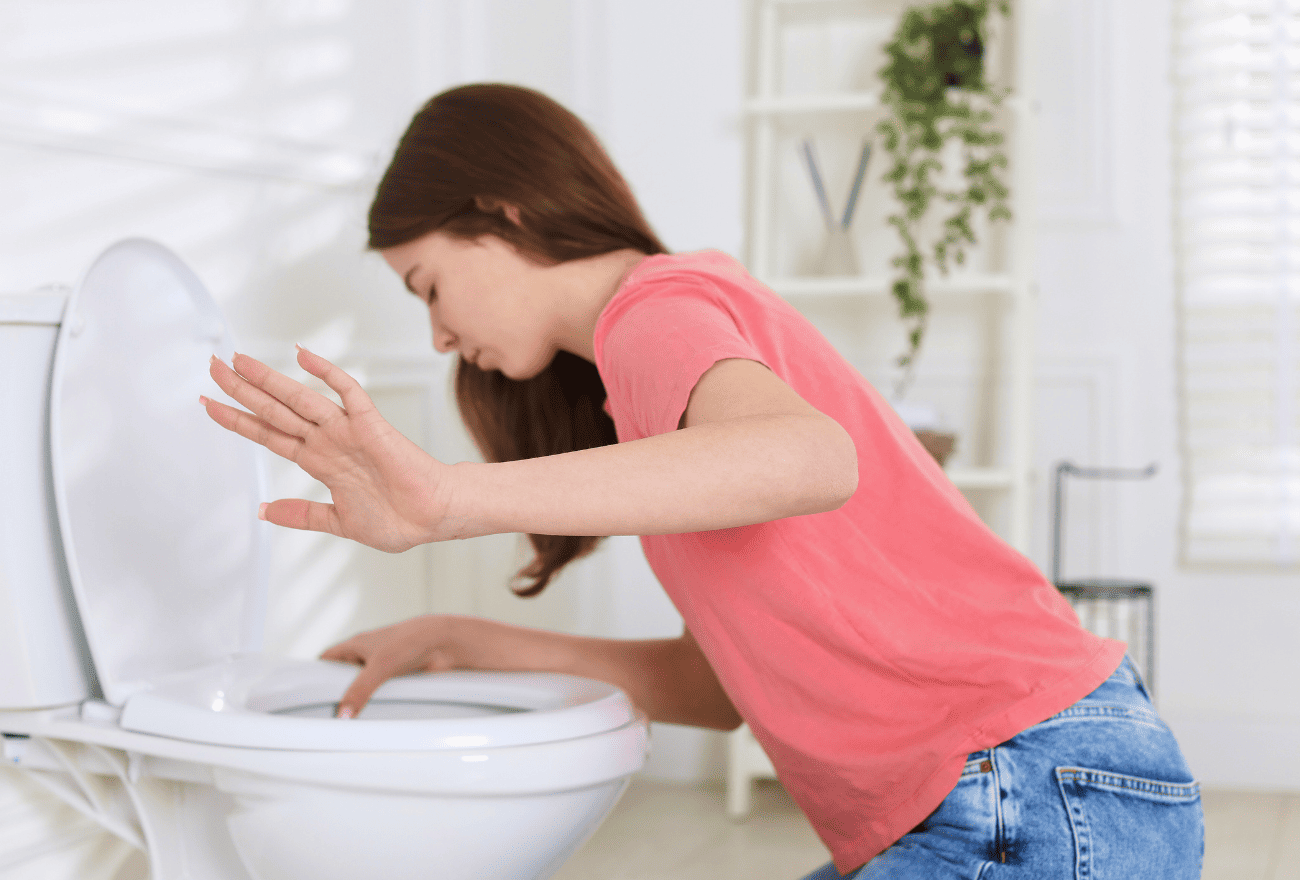 Vertiges et nausée d'une femme positionnée au-dessus de la cuvette des toilettes