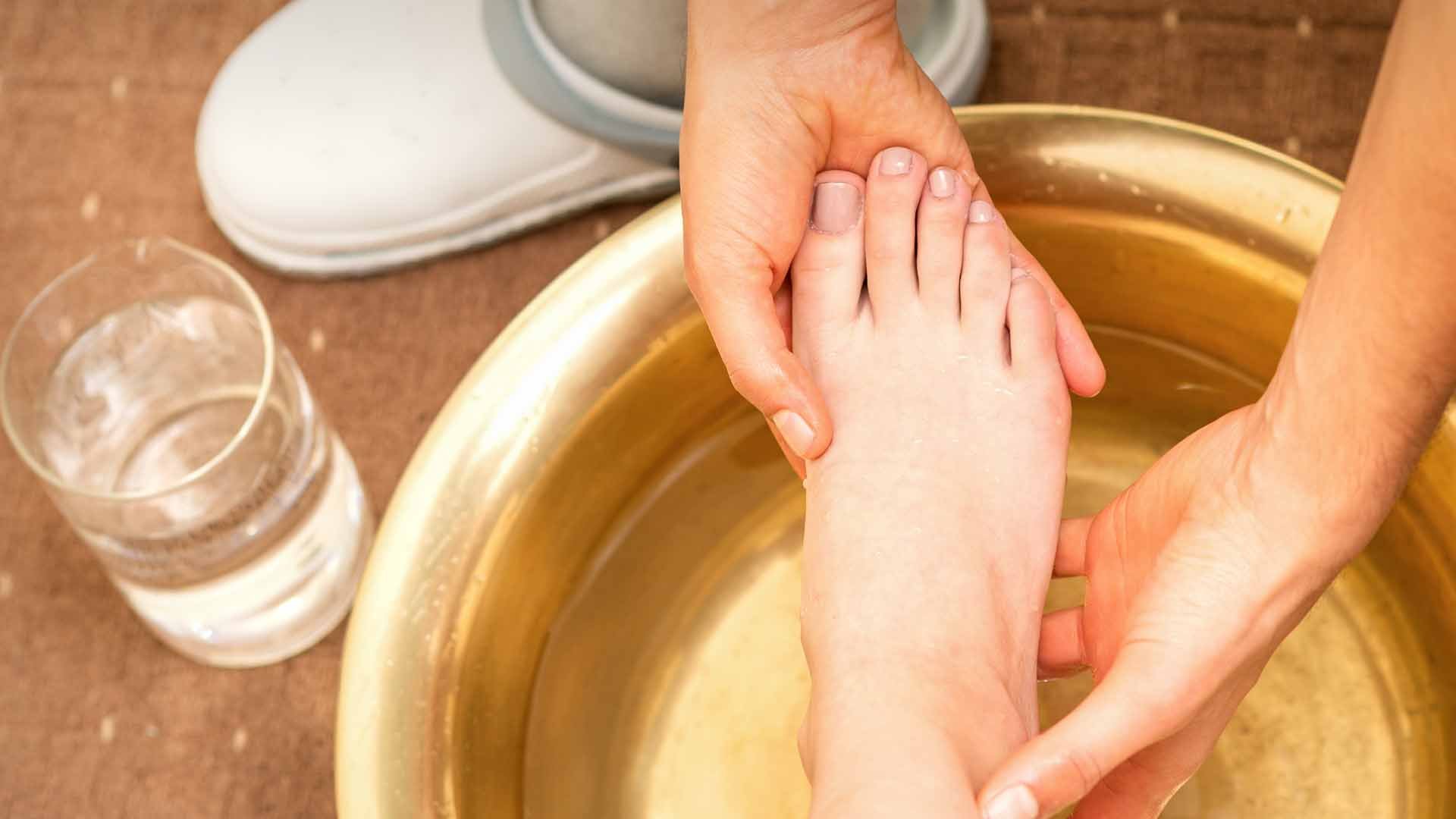 Personne réalisant un bain de pied à une autre personne qui a un panaris.