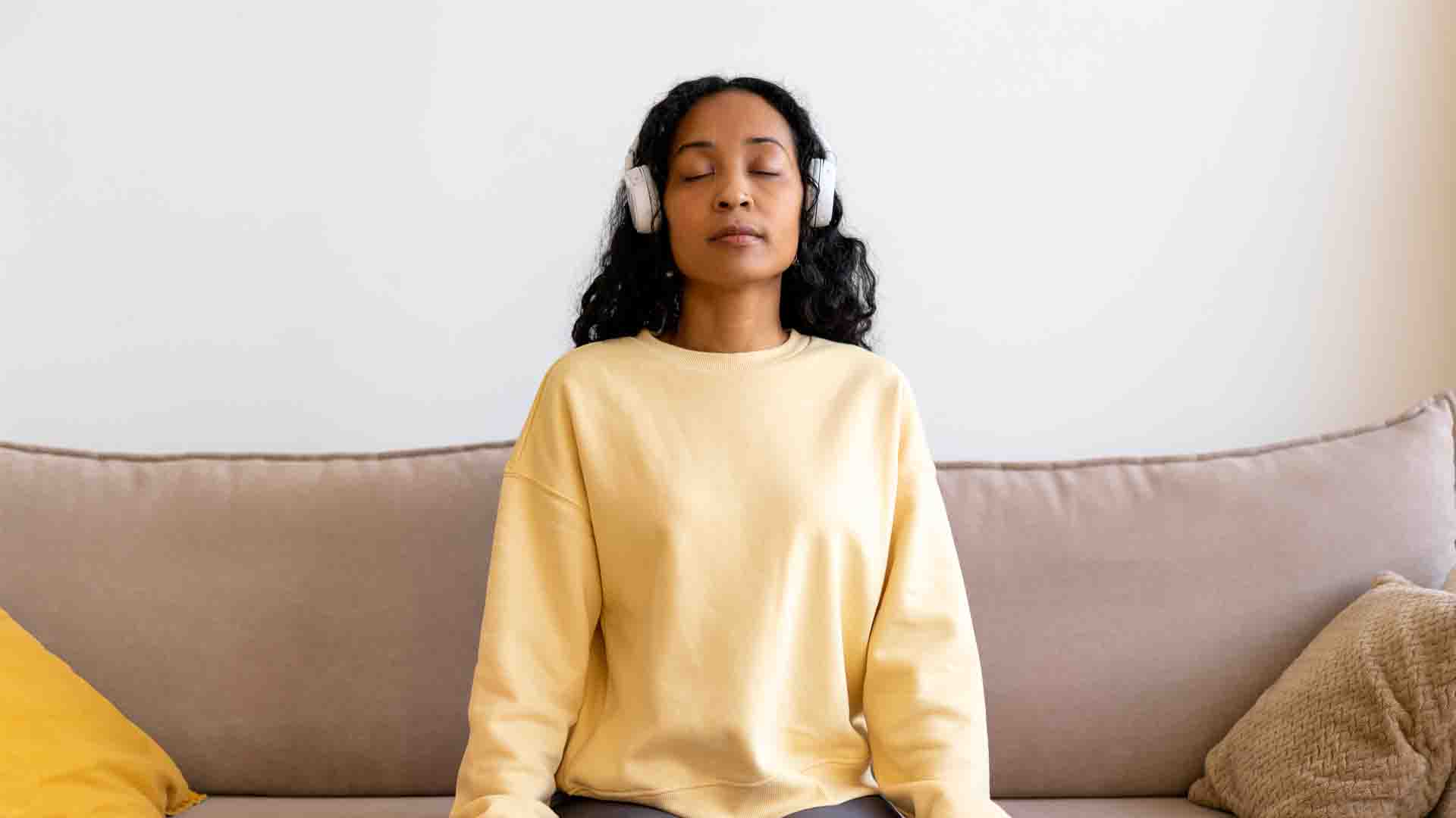 femme assise sur un canapé pratiquant la méditation de pleine conscience