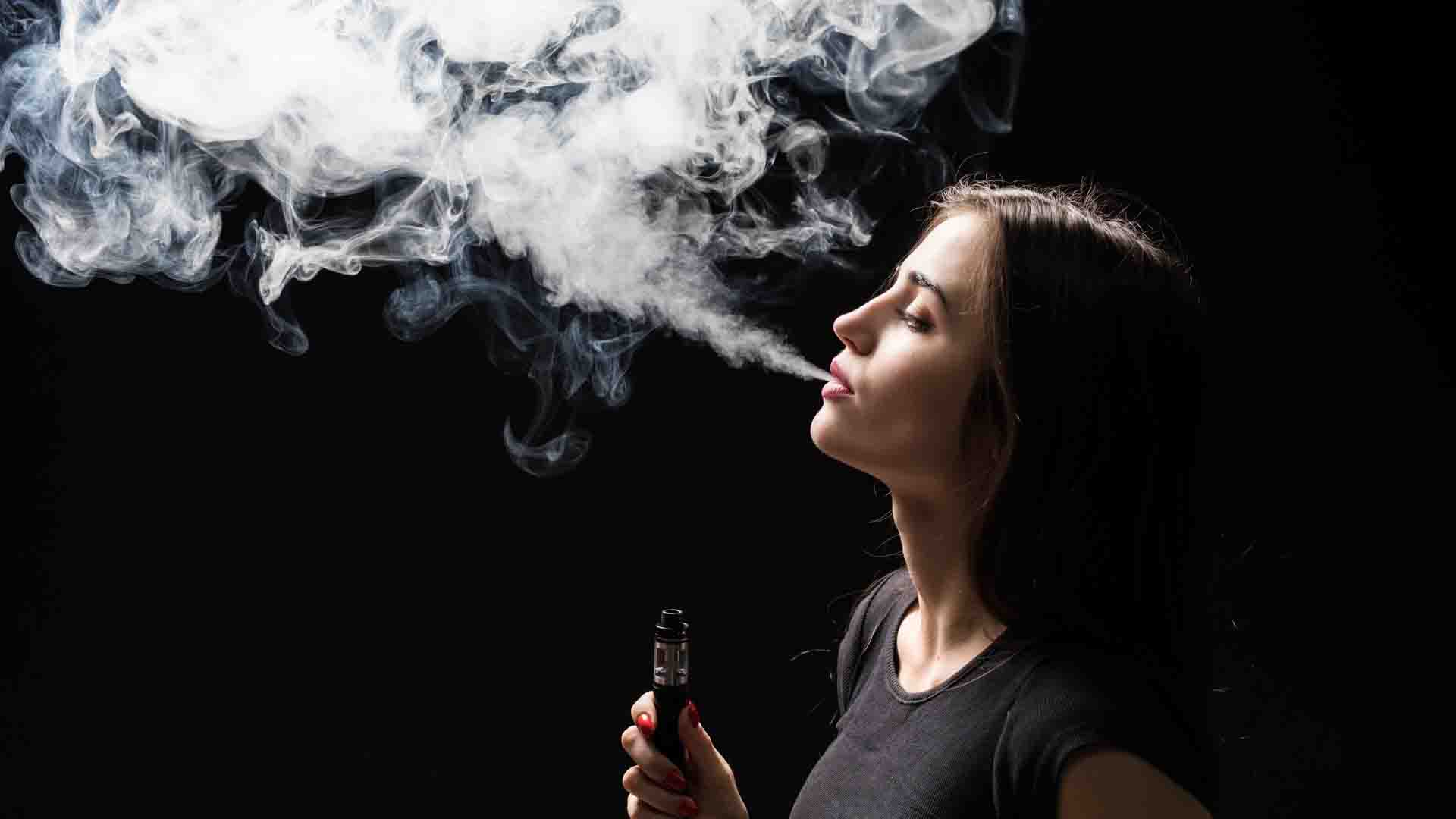 Une femme utilisant sans danger la cigarette électronique et entourée de vapeur et de nicotine